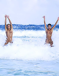 Two sexy girls are nude in the ocean and splashing in the waves looks like a joy.
